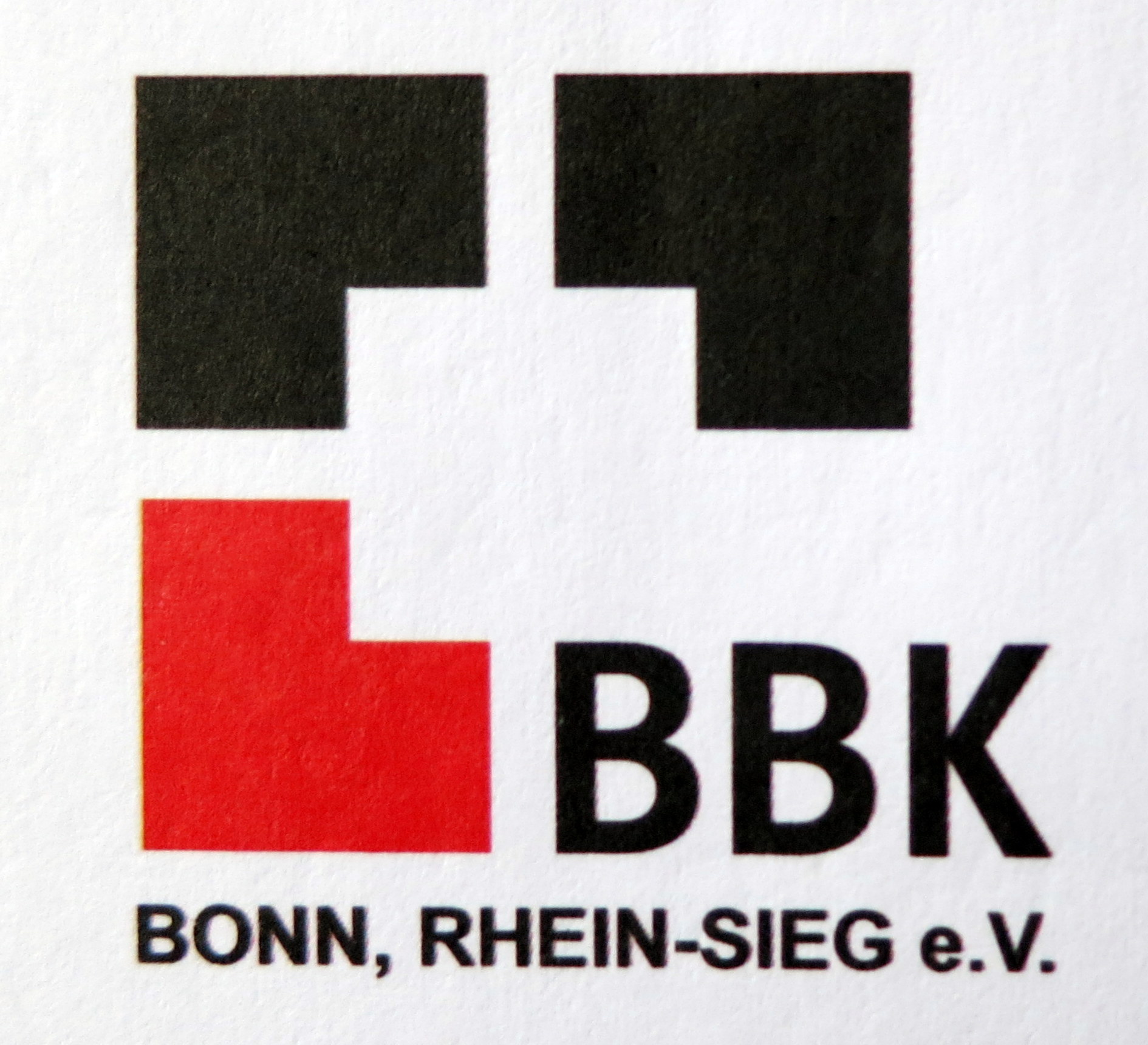 Das Bild zeigt das aktuelle Logo des BBK Bonn - Rhein/Sieg. Zu sehen ist ein offenes Quadrat, angedeutet durch verschiedenfarbige Winkel und den Schriftzug BBK. In der ersten Zeile sind zwei schwarze Winkel zu sehen, in der zweiten Zeile links ein roter Winkel, rechts die Großbuchstaben BBK in schwarzer Farbe, in der dritten Zeile die Worte Bonn, Rhein-Sieg e.V. in schwarzer Farbe, Großbuchstaben.